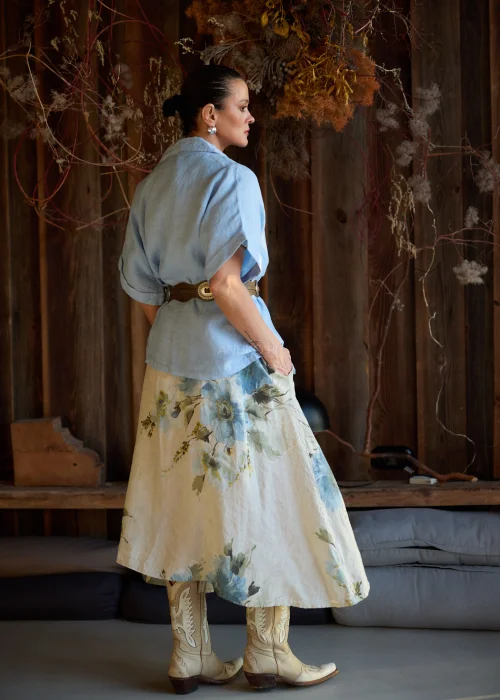 Lniana marynarka damska w kolorze baby blue o luźnym kroju, z krótkim rękawem i klasycznym kołnierzem, stylizacja warstwowa w naturalnym, eleganckim klimacie.