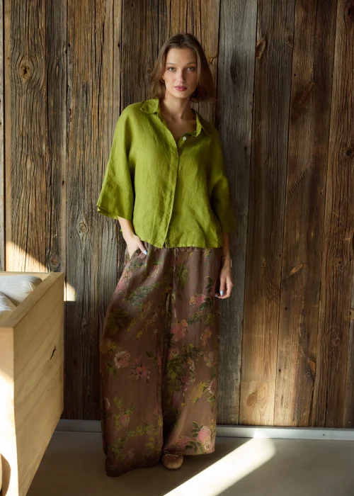 Szerokie spodnie damskie z wysokim stanem w brązowym kolorze z kwiatowym wzorem, o luźnym, lejącym kroju z elastyczną talią, stylizacja w naturalnym, boho klimacie.