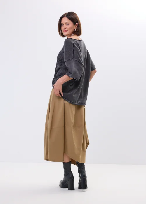 Spódnica midi w karmelowym odcieniu o asymetrycznym, lekko oversize’owym fasonie. Model z efektownymi przeszyciami i dużą kieszenią po boku nadaje stylizacji nowoczesnego charakteru i swobodnego ruchu.