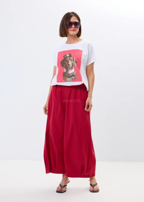 Biały damski t-shirt oversize z nadrukiem jamnika w eleganckiej stylizacji, zestawiony z malinowymi spodniami.