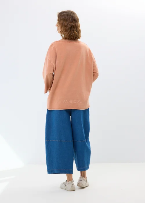 Oversize’owa bluzka w morelowym odcieniu z szerokimi rękawami i haftowanym kwiatem. Swobodny fason zapewnia wygodę i casualowy styl.