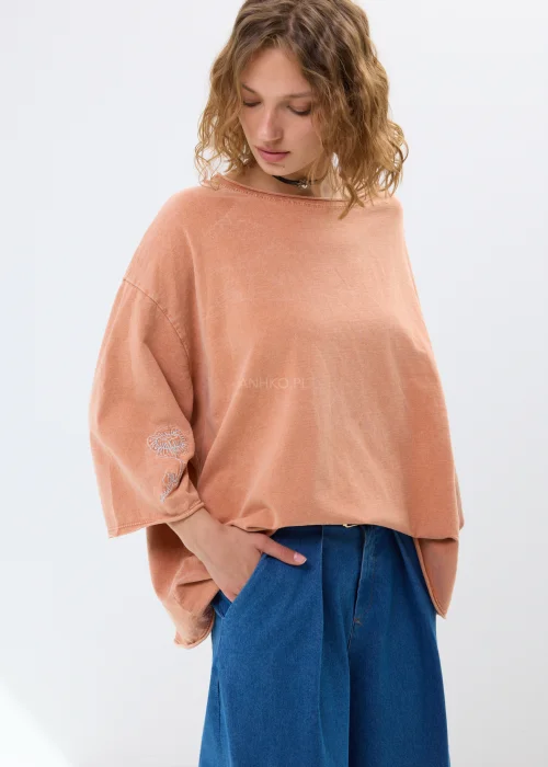 Oversize’owa bluzka w morelowym odcieniu z szerokimi rękawami i haftowanym kwiatem. Swobodny fason zapewnia wygodę i casualowy styl.