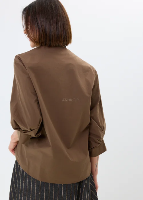 Brązowa bluzka damska z kopertowym przodem i efektownym wiązaniem. Elegancki model z bufiastymi rękawami i luźnym fasonem podkreśla nowoczesny charakter stylizacji.
