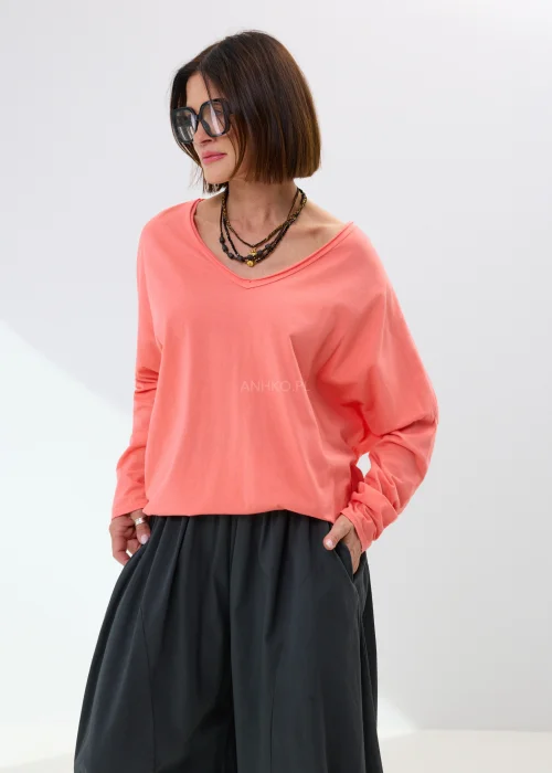 Oversize’owa bluzka damska w jasnoróżowym odcieniu z dekoltem V-neck i luźnym fasonem. Miękko układa się na sylwetce, tworząc wygodną stylizację z szerokimi spodniami lub spódnicą maxi w casualowym stylu.