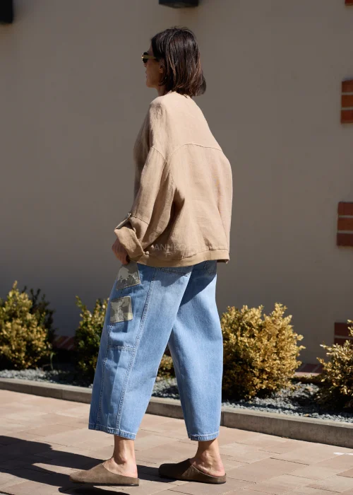 Damska lniana kurtka cappuccino z luźnym fasonem i szerokimi rękawami w casualowej stylizacji z jeansami.