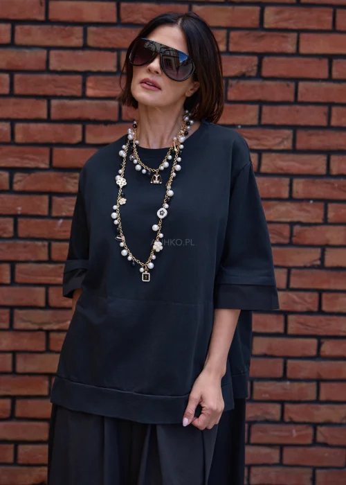 Czarna sukienka oversize midi z szerokim rękawem i minimalistycznym fasonem w nowoczesnej miejskiej stylizacji.