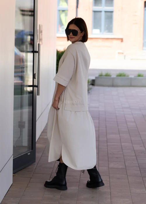 Beżowa sukienka oversize midi z krótkim rękawem i minimalistycznym fasonem w nowoczesnej miejskiej stylizacji.