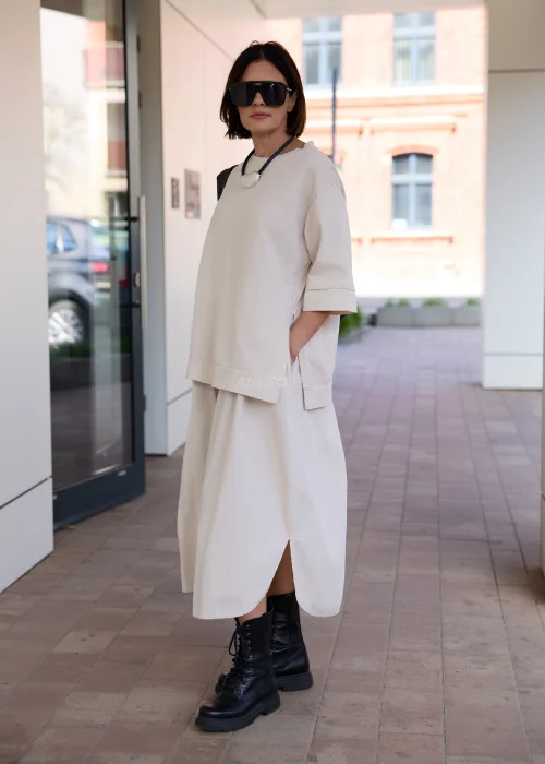 Beżowa sukienka oversize midi z krótkim rękawem i minimalistycznym fasonem w nowoczesnej miejskiej stylizacji.