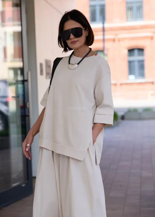 Beżowa sukienka oversize midi z krótkim rękawem i minimalistycznym fasonem w nowoczesnej miejskiej stylizacji.