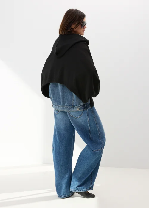 Czarna bluza damska oversize z kapturem i jeansowymi kieszeniami na suwak w nowoczesnym streetwearowym stylu.