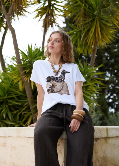 Biały t-shirt z modnym nadrukiem torebki i dekoracyjnych detali. Luźny fason z krótkim rękawem doskonale komponuje się z czarną lnianą spódnicą w casualowej stylizacji.