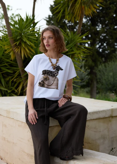 Biały t-shirt z modnym nadrukiem torebki i dekoracyjnych detali. Luźny fason z krótkim rękawem doskonale komponuje się z czarną lnianą spódnicą w casualowej stylizacji.