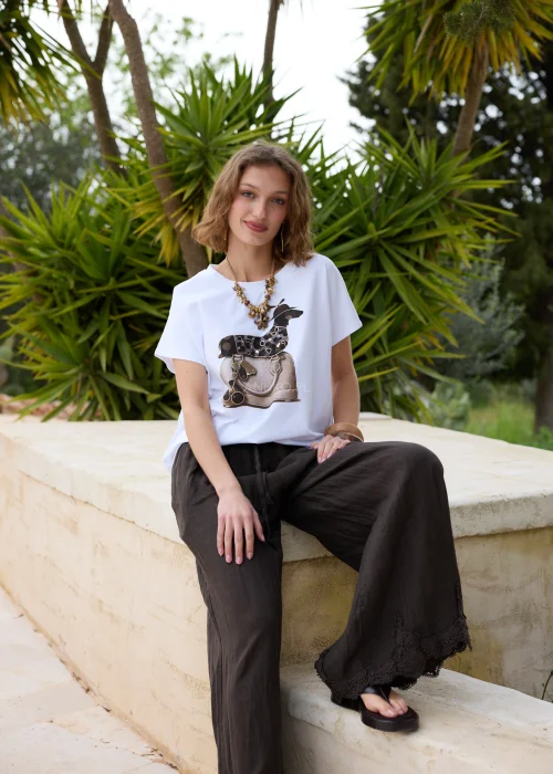 Biały t-shirt z modnym nadrukiem torebki i dekoracyjnych detali. Luźny fason z krótkim rękawem doskonale komponuje się z czarną lnianą spódnicą w casualowej stylizacji.