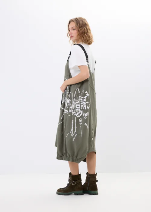 Khaki sukienka ogrodniczka z nadrukami, dużymi kieszeniami i regulowanymi szelkami. Luźny model w miejskim stylu z nowoczesnymi detalami i asymetrycznym fasonem.