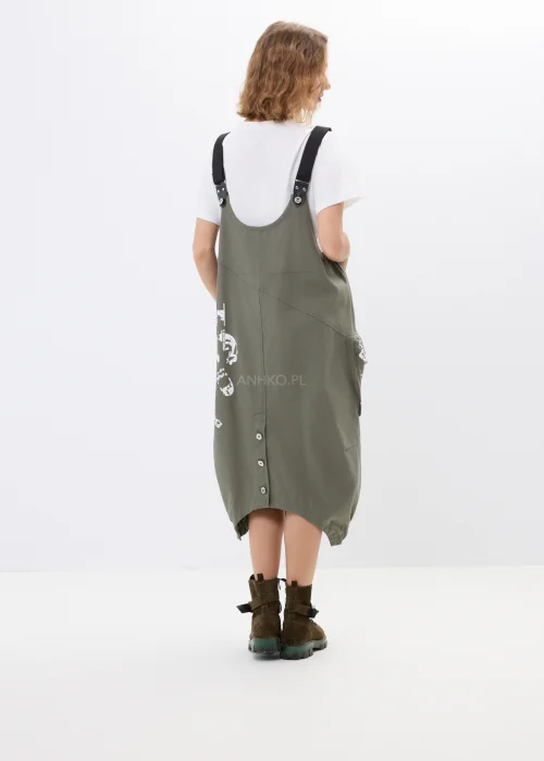 Khaki sukienka ogrodniczka z nadrukami, dużymi kieszeniami i regulowanymi szelkami. Luźny model w miejskim stylu z nowoczesnymi detalami i asymetrycznym fasonem.