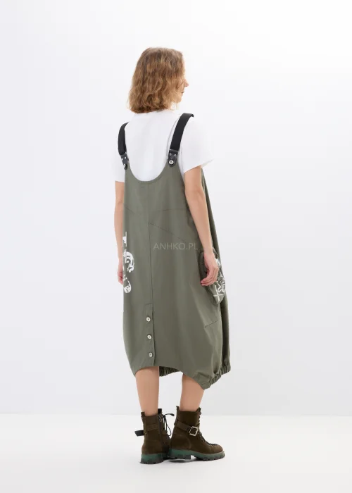 Khaki sukienka ogrodniczka z nadrukami, dużymi kieszeniami i regulowanymi szelkami. Luźny model w miejskim stylu z nowoczesnymi detalami i asymetrycznym fasonem.