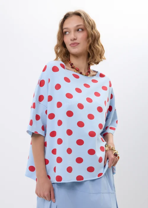 Niebieska bluzka oversize w czerwone grochy z krótkim rękawem i luźnym fasonem. Lekki materiał pięknie układa się na sylwetce, tworząc kobiecą stylizację w retro klimacie z wyrazistym printem.