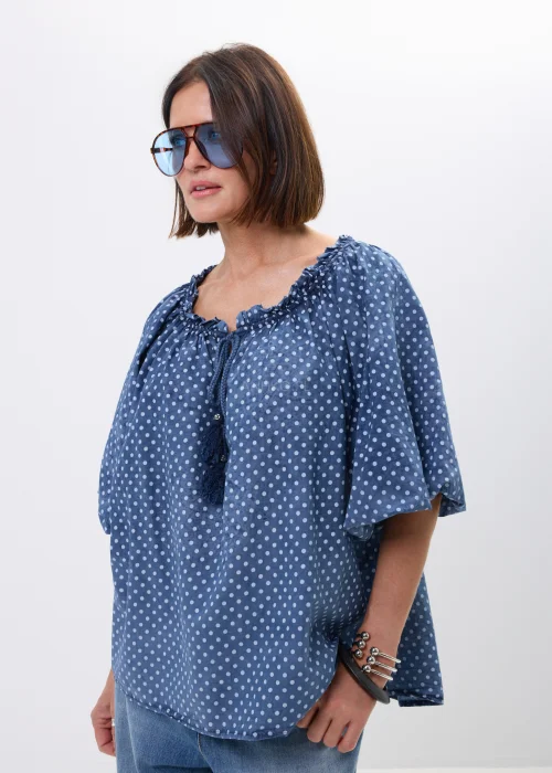 Bluzka damska oversize w kolorze granatowym w drobne groszki. Zwiewny model z szerokimi rękawami i wiązaniem przy dekolcie w stylu boho świetnie komponuje się z jeansami oraz casualowymi stylizacjami.