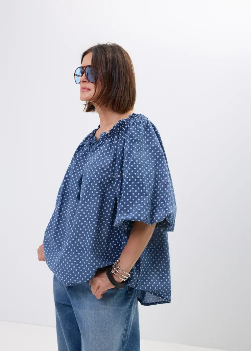 Bluzka damska oversize w kolorze granatowym w drobne groszki. Zwiewny model z szerokimi rękawami i wiązaniem przy dekolcie w stylu boho świetnie komponuje się z jeansami oraz casualowymi stylizacjami.