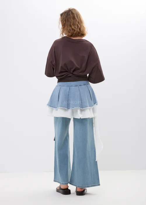 Jeansowa spódniczka mini z plisowanym fasonem i asymetryczną warstwą tiulu. Oryginalny model z surowym wykończeniem i dekoracyjnymi paskami idealny do stylizacji streetwear oraz fashion looków z charakterem.