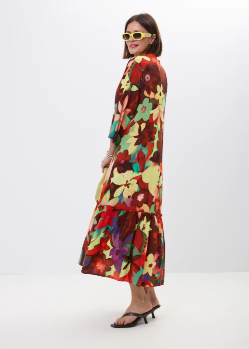 Długa sukienka maxi w kolorowy kwiatowy print z falbaną i rękawem 3/4. Zwiewny model z guziczkami i luźnym fasonem idealny do letnich stylizacji boho oraz casual chic.