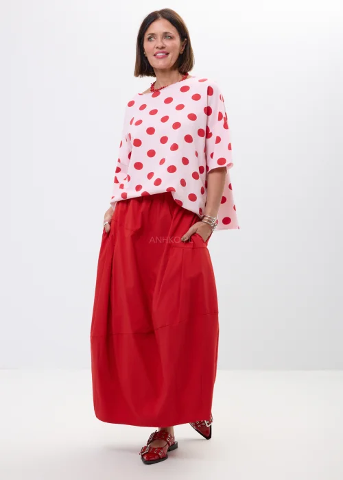 Różowa bluzka oversize w czerwone grochy z szerokim rękawem i minimalistycznym dekoltem. Kobiecy model idealny do  stylizacji w klimacie retro chic i casual fashion.