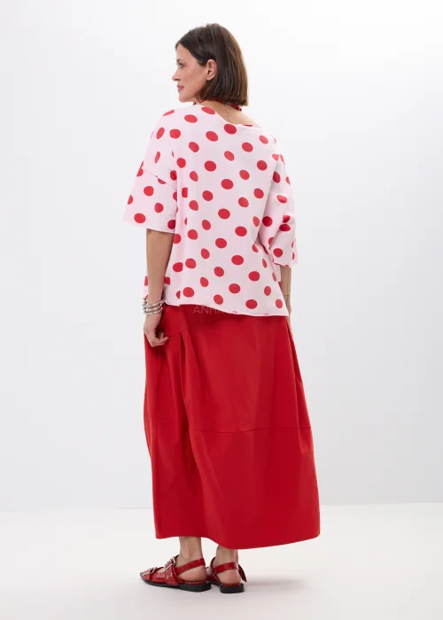 Różowa bluzka oversize w czerwone grochy z szerokim rękawem i minimalistycznym dekoltem. Kobiecy model idealny do  stylizacji w klimacie retro chic i casual fashion.