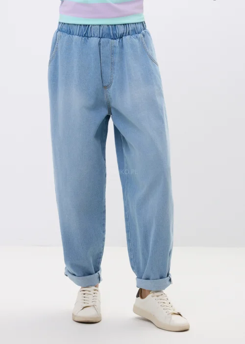 Jasne jeansy damskie o luźnym fasonie baggy z elastyczną gumką w pasie. Model z podwiniętymi nogawkami i miękkim denimem zapewnia wygodę oraz swobodny, miejski charakter stylizacji.
