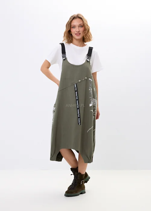 Khaki sukienka ogrodniczka z nadrukami, dużymi kieszeniami i regulowanymi szelkami. Luźny model w miejskim stylu z nowoczesnymi detalami i asymetrycznym fasonem.