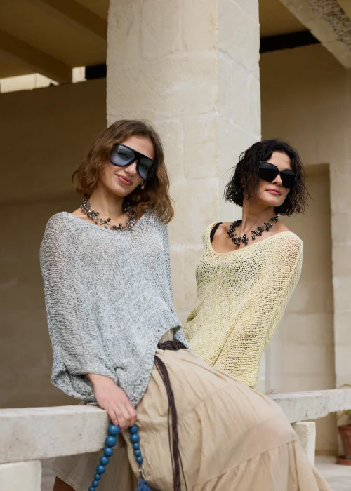 Żółty sweter damski o luźnym oversize'owym kroju z ażurowym splotem i szerokimi rękawami. Lekka dzianina nadaje stylizacji swobodny charakter i doskonale komponuje się z lnianymi spodniami.