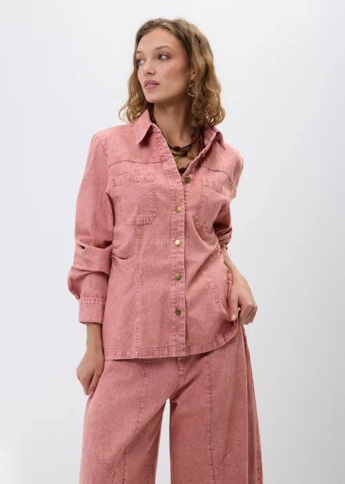 Różowa koszula jeansowa z długim rękawem, kołnierzykiem i zapięciem na napy. Model z kieszeniami na piersi i dopasowanym fasonem tworzy modną stylizację denim total look w kobiecym wydaniu.