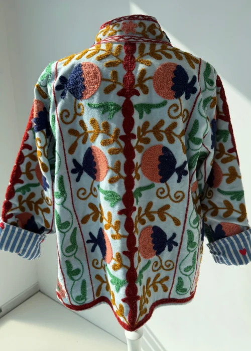 Elegancki welurowy żakiet damski z bogatym haftem kwiatowym na jasnym tle.