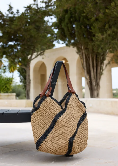 Pleciona torba shopper w kolorze camelowym z kontrastowymi czarnymi pasami i długimi uchwytami w odcieniu brązu. Pojemny model o naturalnej strukturze w stylu boho, idealny do codziennych stylizacji i wyjazdów.