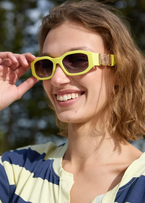 Limonkowe damskie okulary przeciwsłoneczne o geometrycznej prostokątnej oprawce z ciemnymi szkłami i ozdobnym metalowym detalem przy zausznikach.