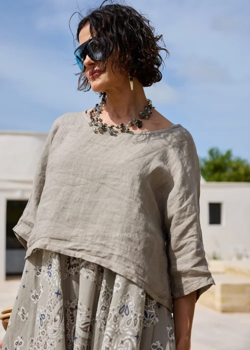 Sukienka w kolorze taupe z ozdobnym wzorem paisley w odcieniach beżu i błękitu. Zwiewny model o luźnym kroju z lnianą górą i rozkloszowanym dołem prezentowany w naturalnej stylizacji.