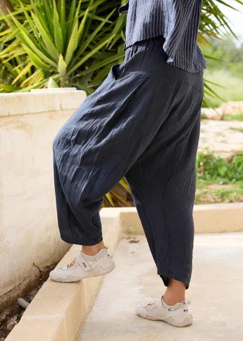Granatowe lniane spodnie damskie o luźnym kroju z obniżonym krokiem i szerokimi nogawkami. Komfortowy model w stylu casual zestawiony z lnianą koszulą w paski.