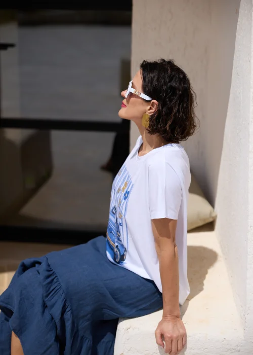 Biały T-shirt damski z nadrukiem niebieskiego retro samochodu i dekoracyjnymi kwiatami 3D, zestawiony z granatową spódnicą. Casualowy model o luźnym kroju idealny do codziennych stylizacji w letnim, miejskim stylu.