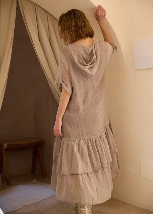 Lniana sukienka maxi z kapturem w odcieniu taupe, z dekoracyjną falbaną u dołu i podwijanymi rękawami. Swobodny fason w stylu boho doskonale sprawdzi się w naturalnych, codziennych i eleganckich stylizacjach.