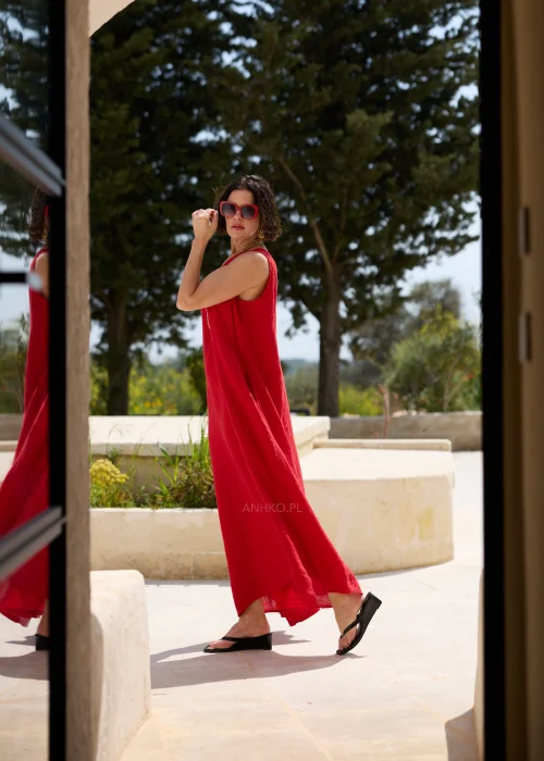 Czerwona lniana sukienka maxi bez rękawów z okrągłym dekoltem, luźnym fasonem i praktycznymi kieszeniami. Minimalistyczna stylizacja podkreśla elegancki, swobodny charakter modelu.