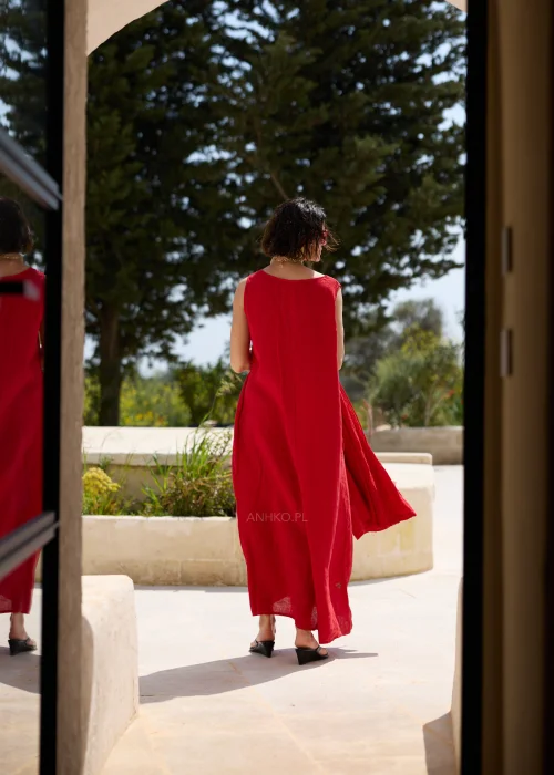 Czerwona lniana sukienka maxi bez rękawów z okrągłym dekoltem, luźnym fasonem i praktycznymi kieszeniami. Minimalistyczna stylizacja podkreśla elegancki, swobodny charakter modelu.