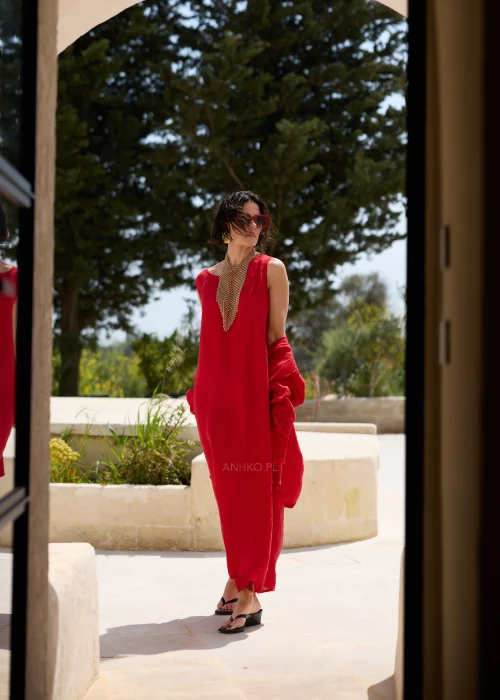 Czerwona lniana sukienka maxi bez rękawów z okrągłym dekoltem, luźnym fasonem i praktycznymi kieszeniami. Minimalistyczna stylizacja podkreśla elegancki, swobodny charakter modelu.