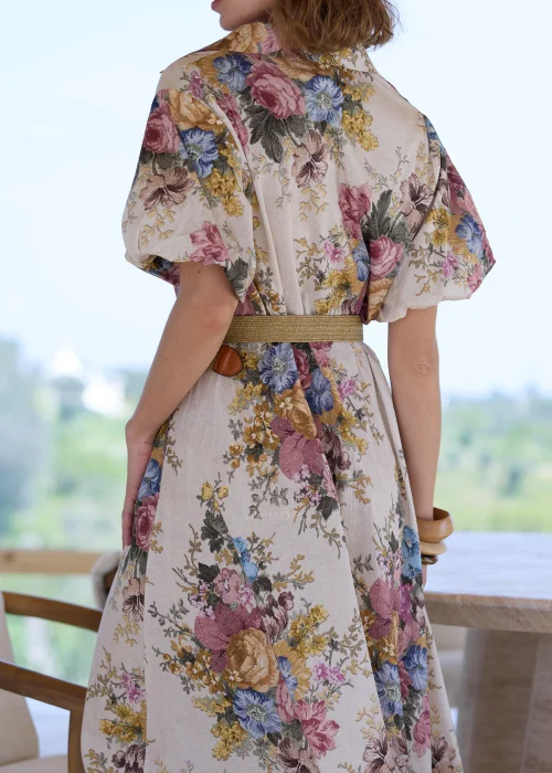 Sukienka maxi w kwiatowy wzór w stylu boho, z krótkimi bufiastymi rękawami i paskiem podkreślającym talię. Romantyczna stylizacja z kowbojkami i okularami przeciwsłonecznymi idealnie podkreśla artystyczny, rustykalny charakter modelu.