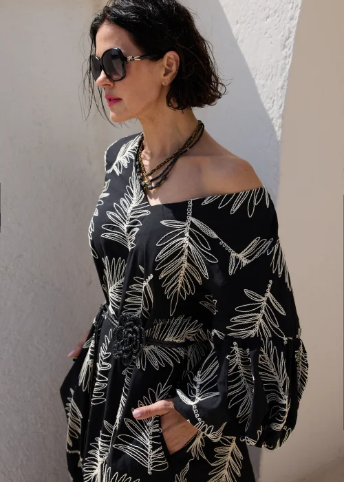 Czarna sukienka midi z haftowanym wzorem liści, bufiastymi rękawami i paskiem podkreślającym talię. Elegancki model o luźnym fasonie, idealny na wyjątkowe okazje i stylizacje w klimacie boho.
