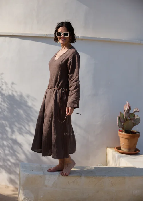 Brązowa lniana sukienka midi z dekoltem V i długimi rękawami o luźnym, naturalnym fasonie. Minimalistyczny krój podkreśla elegancję stylizacji w klimacie boho i slow fashion.
