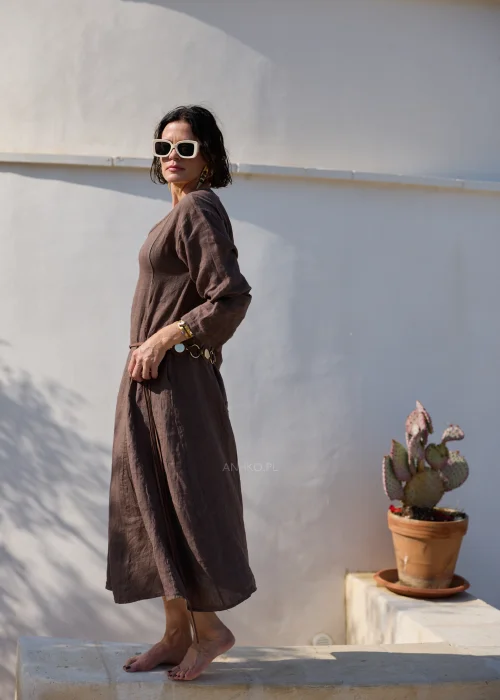 Brązowa lniana sukienka midi z dekoltem V i długimi rękawami o luźnym, naturalnym fasonie. Minimalistyczny krój podkreśla elegancję stylizacji w klimacie boho i slow fashion.