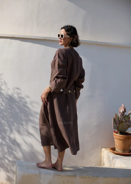 Brązowa lniana sukienka midi z dekoltem V i długimi rękawami o luźnym, naturalnym fasonie. Minimalistyczny krój podkreśla elegancję stylizacji w klimacie boho i slow fashion.