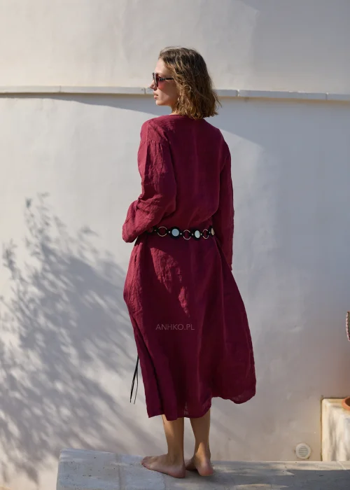 Bordowa lniana sukienka midi z dekoltem V i długimi rękawami o luźnym, naturalnym fasonie. Minimalistyczny krój podkreśla elegancję stylizacji w klimacie boho i slow fashion.