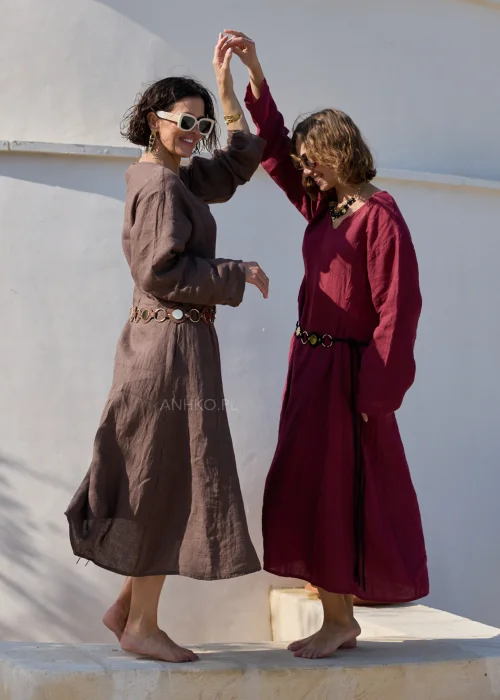 Bordowa lniana sukienka midi z dekoltem V i długimi rękawami o luźnym, naturalnym fasonie. Minimalistyczny krój podkreśla elegancję stylizacji w klimacie boho i slow fashion.
