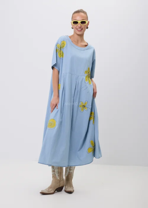 Błękitna sukienka maxi oversize z krótkim rękawem i efektownym nadrukiem dużych żółtych kwiatów. Luźny fason z odcięciem pod biustem zapewnia swobodę noszenia i tworzy lekką, kobiecą stylizację na co dzień.