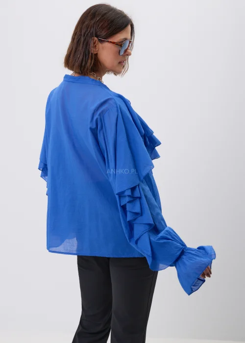Elegancka damska bluzka oversize w intensywnym kobaltowym kolorze z efektownymi falbanami przy dekolcie i długimi rękawami zakończonymi marszczeniem.